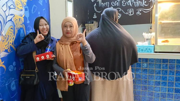 GRATIS: Dua pemilih menikmati makanan gratis dari Dalwa Fried Chicken, Bangil setelah memilih di TPS.