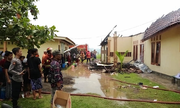 PEMBASAHAN: Petugas Damkar Kota Pasuruan melakukan pembasahan pada gudang Ponpes Ihya&rsquo;us Sunnah yang terbakar, Sabtu (24/2).