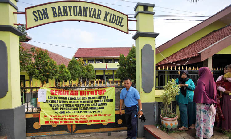 TAK BISA MASUK: Banner yang terpasang di gerbang SDN Banyuanyar Kidul, Jumat (1/3) pagi.