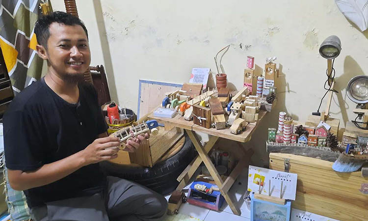BUTUH KETELITIAN: Achmad Adias Wijaya menunjukkan mainan mobil dan rumah karyanya yang dibuat dari limbah kayu pinus dan jati.