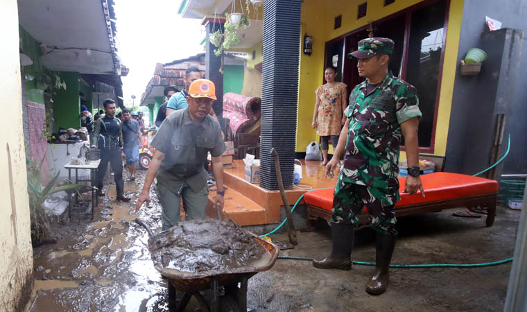 TEBAL: Pj Bupati Probolinggo, Ugas Irwanto mendorong sisa endapan lumpur di rumah warga di Dusun Siwalan, Desa Kedungdalem, Kecamatan Dringu, Selasa (12/3) pagi.
