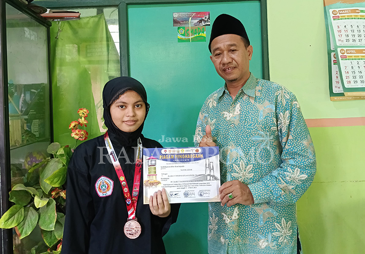 JUARA: Nailil Izzah bersama Kepala SMAI Darut Tauhid Ilyas Mukti, usai menjadi juara I Pencak Silat Kelas Praremaja se-Jatim Bali.