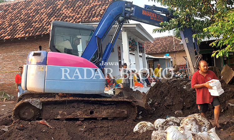 SEWA: Agus Sulistyono, warga Desa Kedungdalem membersihkan material sisa banjir bandang di RT 04/RW 02 menggunakan alat berat yang diperoleh warga dengan cara sewa.