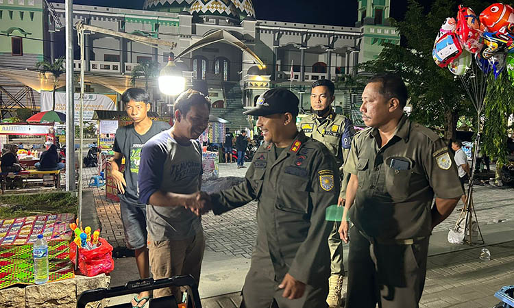 DIIMBAU: Anggota Satpol PP Kota Probolinggo mengimbau pelaku usaha mainan di Alun-Alun Kota Probolinggo untuk tidak beroperasi sampai melewati pukul 22.000, Minggu (24/3).