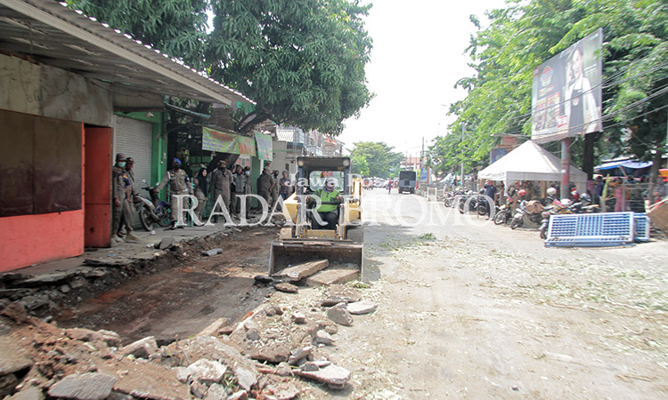 DIBONGKAR: Pembongkaran semen pondasi untuk berjualan pedagang di depan Pasar Semampir dilakukan dengan bantuan mino loader, Jumat (29/3).