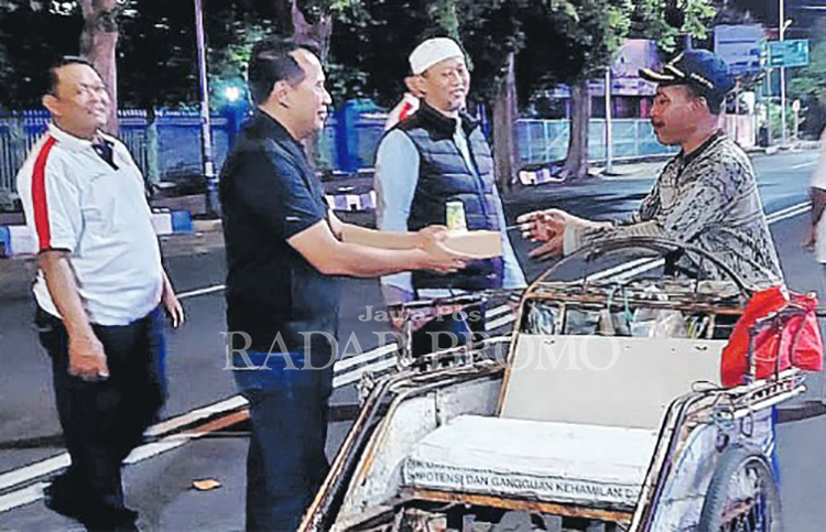BERBAGI: Pj Wali Kota Probolinggo Nurkholis memberikan nasi kotak kepada salah seorang abang becak yang melintas di Jalan Panglima Sudirman, Selasa (2/4).