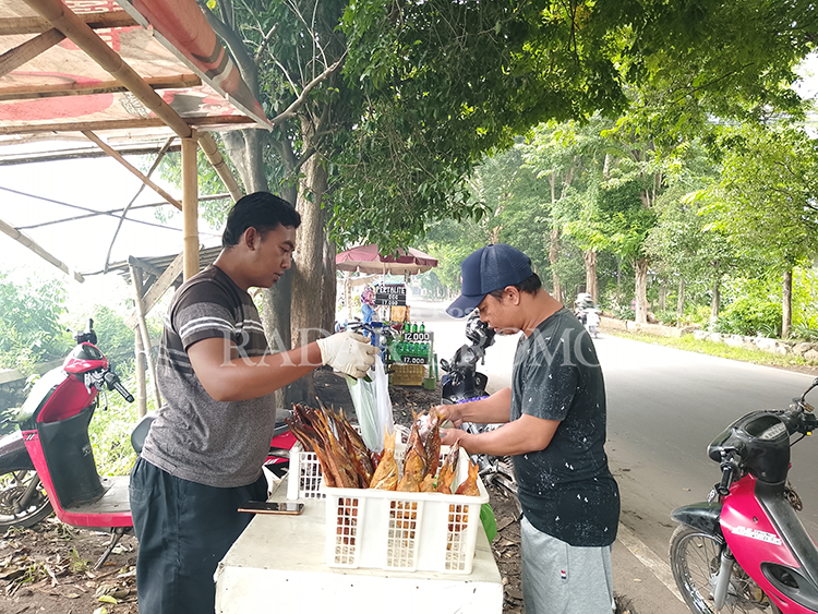 PEDAGANG: Salah satu pedagang ikan asap di jalan brantas saat melayani pembeli.