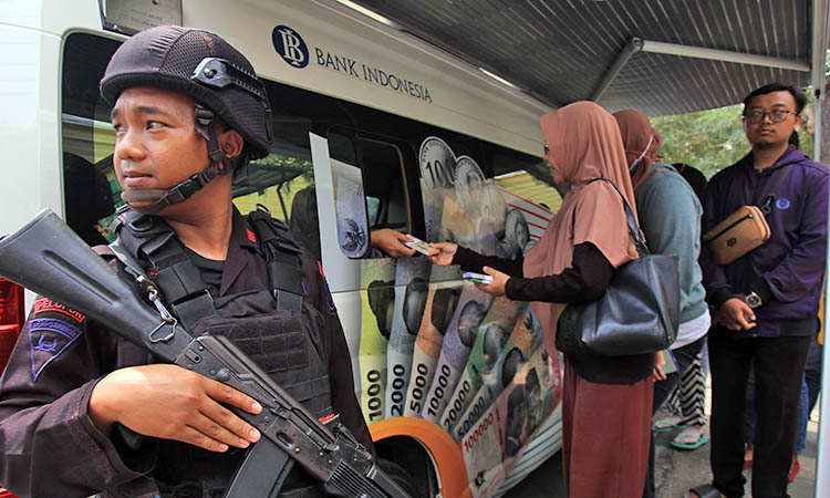 DIJAGA: Layanan penukaran uang baru oleh Bank Indonesia di Kota Pasuruan dijaga dengan ketat petugas Brimob, beberapa waktu lalu.