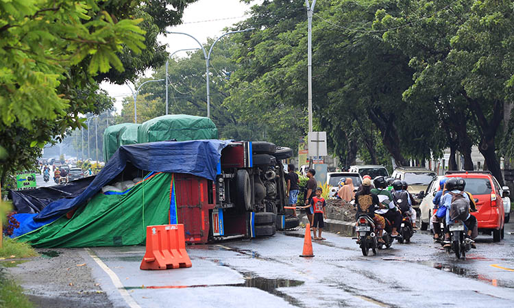 MACET: Truk pakan ternak yang terguling membuat Jalan Raya Kraton, Kelurahan Karangketug, Kecamatan Gadingrejo mengalami kemacetan.