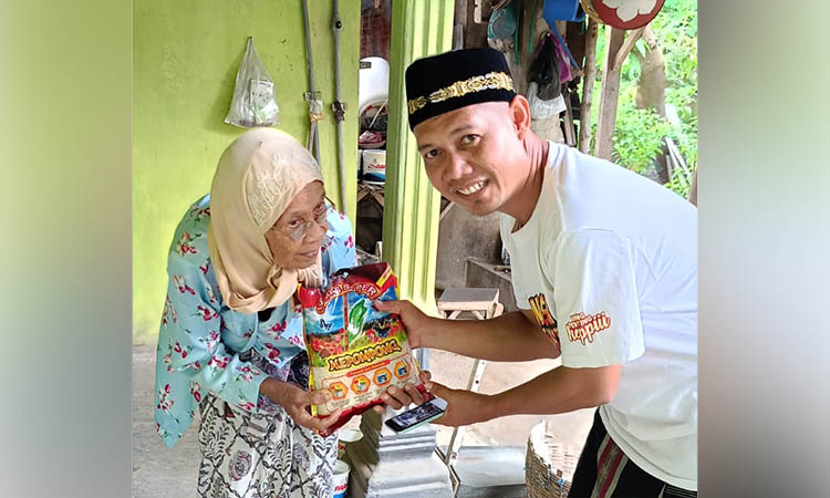 BAGIKAN: Salah satu anggota Karang Taruna yang membagikan sembako kepada warga yang membutuhkan.