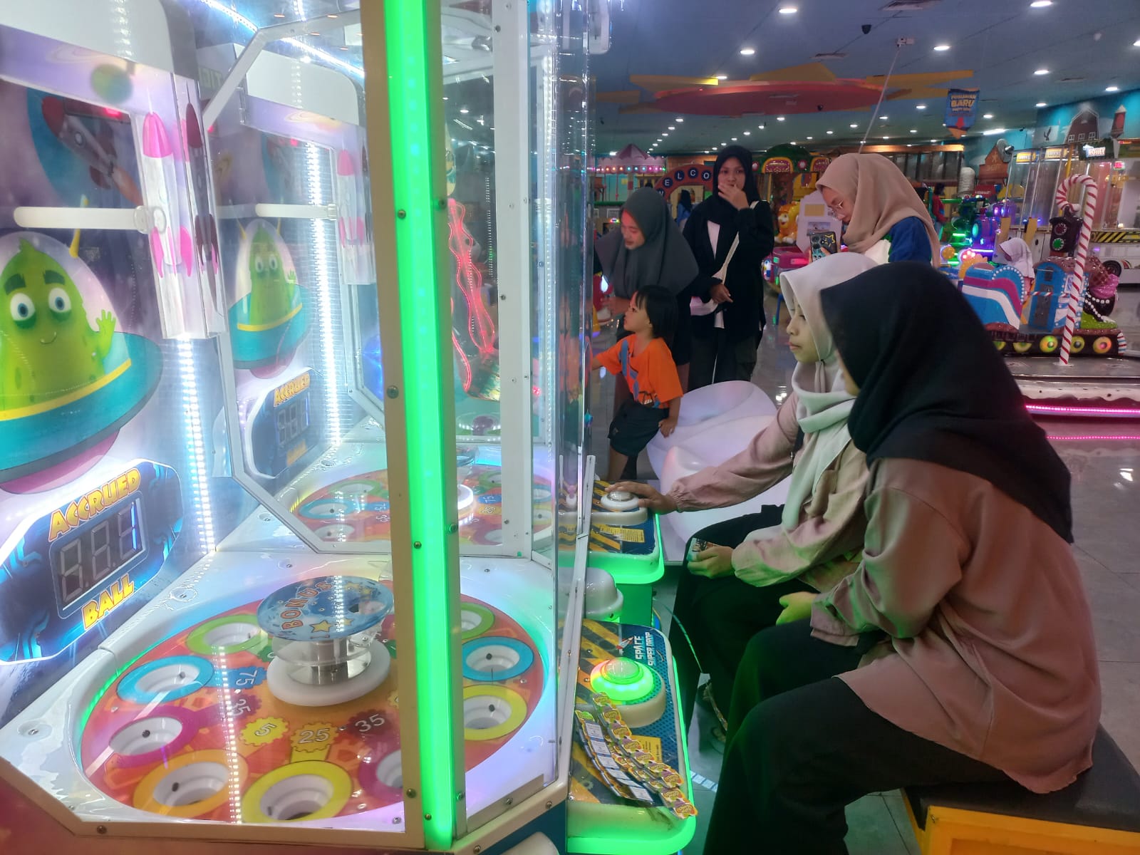SABAR: Nadhisa Ayu Listi Abdulla (kerudung hitam) dan Nazhima Zahra Shafira Putri (kerudung coklat) memastikan bola bisa masuk ke lubang jackpot game Monster Drop Extreme.