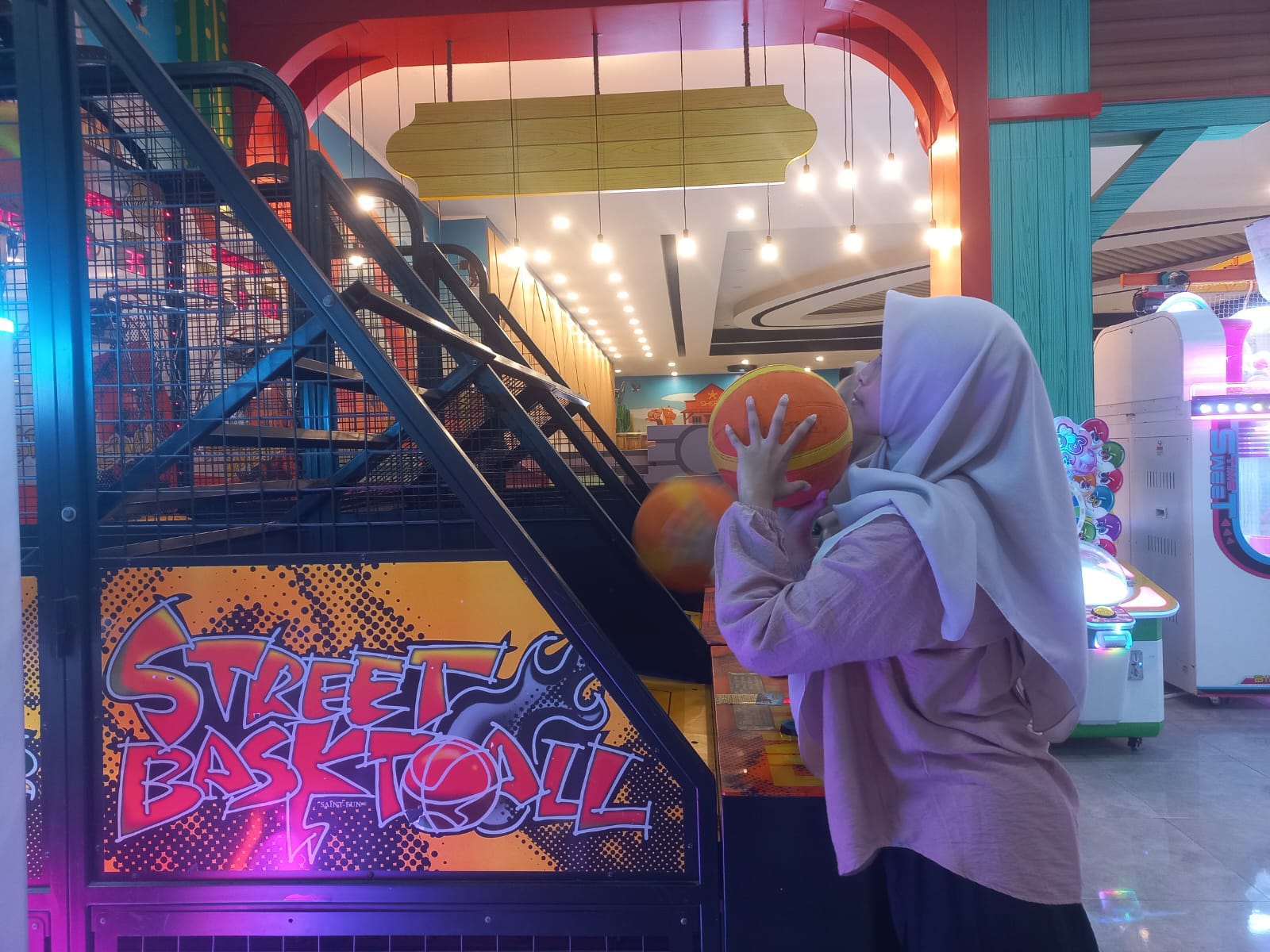 MASUKKAN BOLA: Maulidia Eka Wiliamarta, bermain street basket ball di salah satu game zone di Jalan Dr. Soetomo, Kota Probolinggo.