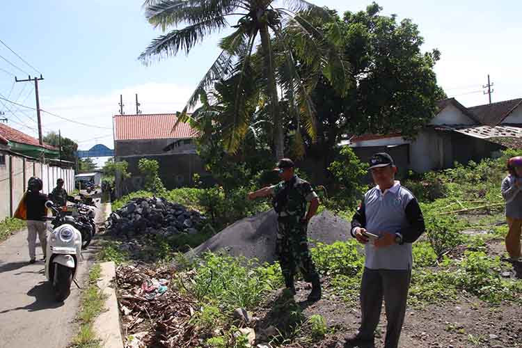 GARAP TPT: Batuud Koramil Leces Peltu Bambang Dwi Asmoro bersama Pendamping Lokal Desa Hel Abdul Rozuq mengecek lokasi pembangunan TPT di RT 03/RW 01 Dusun Krajan.