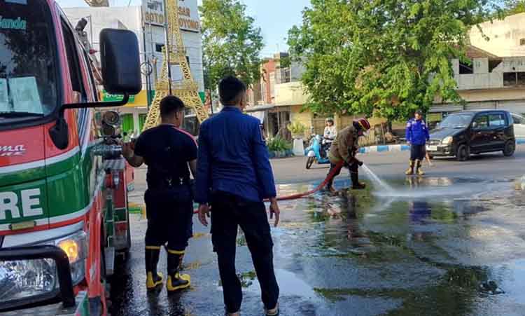 DIBERSIHKAN: Tim Damkar Satpol PP Kota Probolinggo membersihkan tumpahan solar di Tikungan Menara Eiffel, Jalan Pahlawan, Kota Probolinggo, Sabtu (4/5) sore.