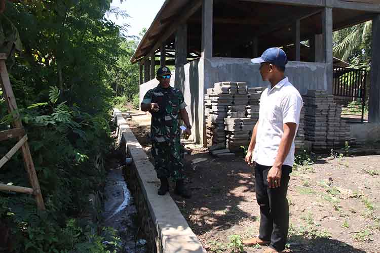 PROYEK TPT: Batuud Koramil Leces Peltu Bambang Dwi Asmoro bersama Pendamping Teknik Infrastruktur Desa Ahmad Faisol Tanjung mengecek proyek TPT di Dusun Pasar Arah.