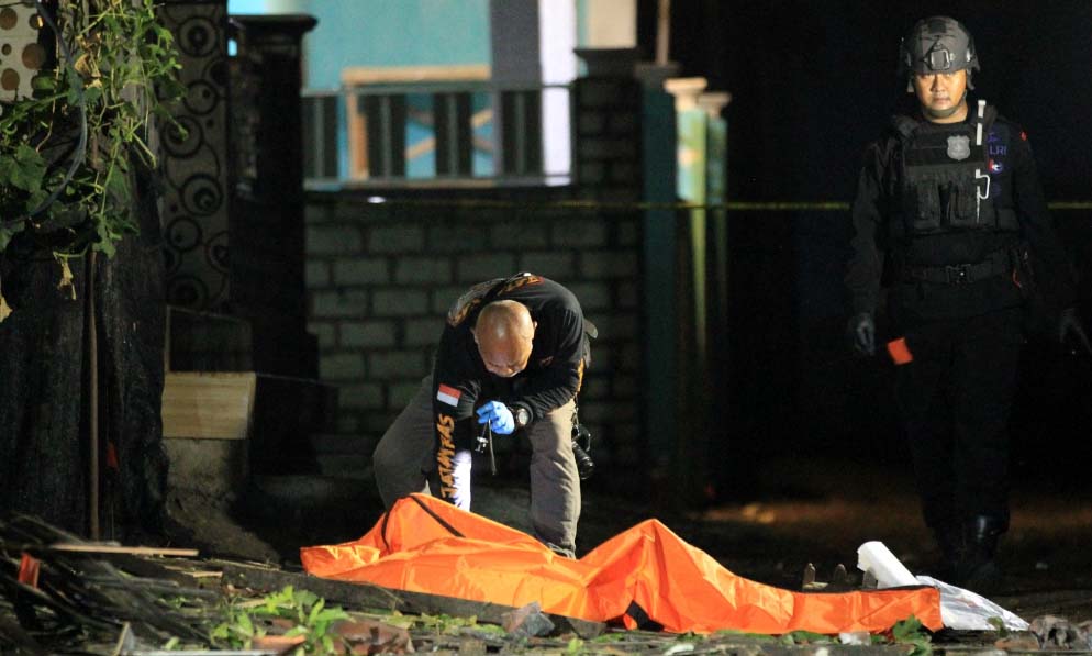 CARI PETUNJUK: Petugas Inafis Polres Pasuruan Kota memilih potongan tubuh manusia di sekitar lokasi kejadian.