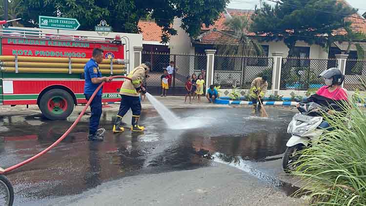 DISEMPROT: Tim Damkar Satpol PP Kota Probolinggo membersihkan tumpahan solar di tikungan Jalan Slamet Riyadi, Kelurahan/Kecamatan Kanigaran, Kota Probolinggo, Rabu (22/5).