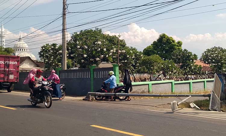 ROBOH: Pengendara motor melintas di sekitar PJU yang roboh akibat dihantam truk saat hendak putar balik, Jumat (31/5) siang. (Moch Vikry Romadhoni/Jawa Pos Radar Bromo)