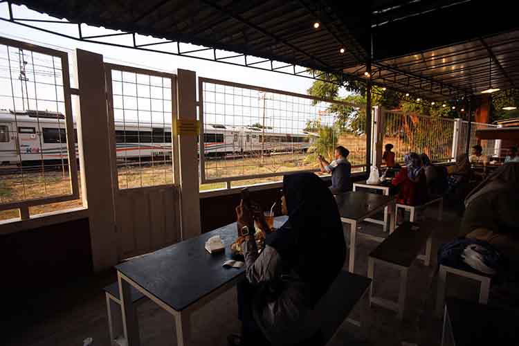 MELINTAS: Suasana lokasi kuliner dengan pemandangan rail view di Kelurahan/Kecamatan Mayangan, Kota Probolinggo, ketika ada kereta api yang melintas.