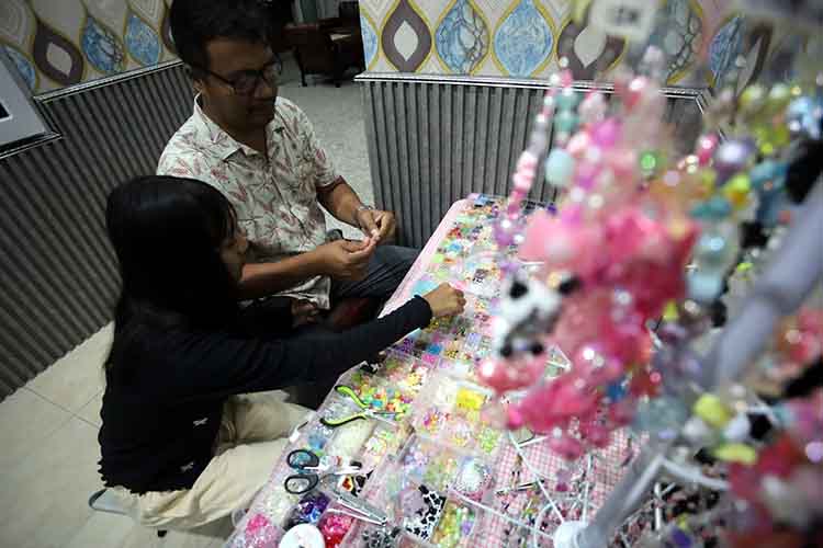 KERJA SAMA: Kinanti Wulan Ramadhani, meronce manik-manik ditemani ayahnya Erik Arfiyanto.