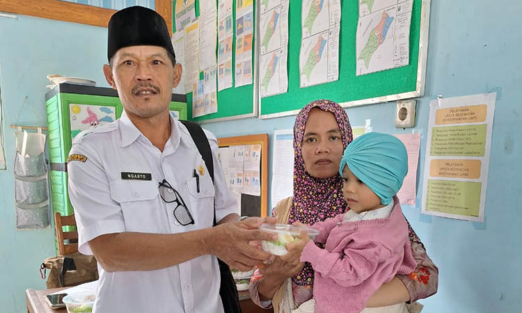 BANTUAN PANGAN: Kepala Desa Negororejo Ngasto memberikan makanan kepada balita desa. Program Pemberian Makanan Tambahan menjadi program rutin desa.