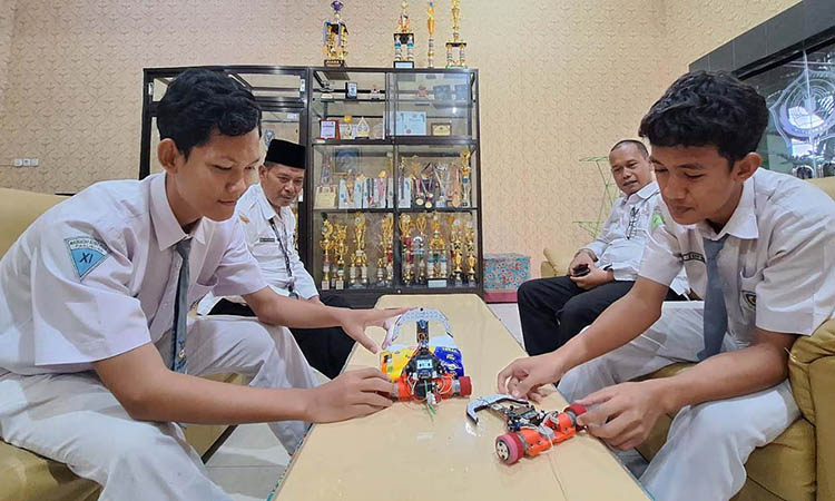 TANGGUH: Akhmad Rikhan Al Zidan dan M. Ravy Habibi memamerkan robot line follower buatannya yang kecepatannya terpaut sepersekian detik ketimbang buatan M. Syifaul Qolbu