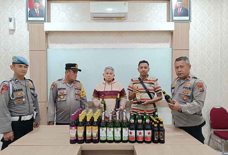 BERALKOHOL: Puluhan botol miras dan pemiliknya (tengah) diamankan ke Mapolsek Prigen.