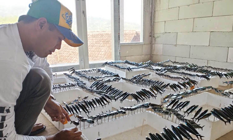 TELITI-TELATEN: Edi Asan Joko melihat umpan pancing produksinya yang sedang dalam proses pengeringan.