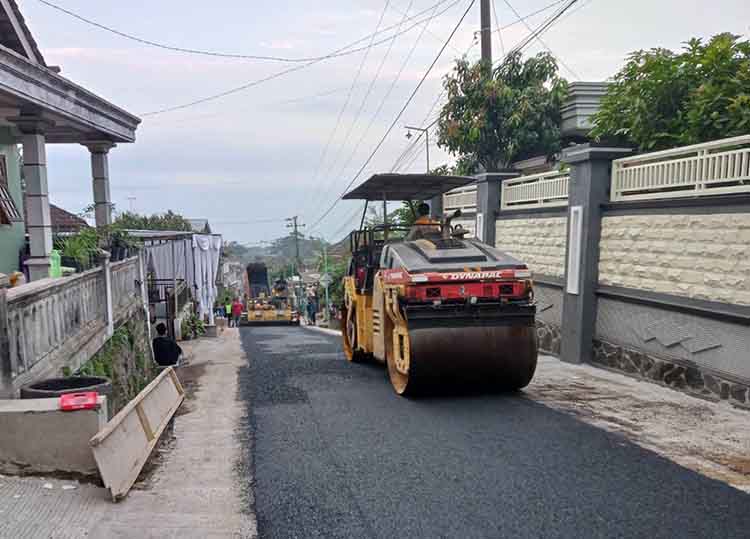 DIHOTMIX: Pekerja saat mengoperasikan alat berat untuk memuluskan jalan Sumberrejo-Tambakwatu. Ditargetkan, bulan ini sudah bisa terselesaikan.