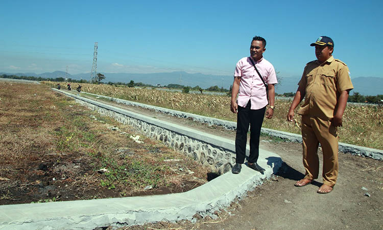 AKSES KE SAWAH: Sekretaris Desa Sumberagung Tri Hardiyanto J (baju pink) bersama Kaur Perencanaan Desa Dedy Indra Ismanto di lokasi pembangunan jalan usaha tani di Desa Sumberagung, Senin (15/7).