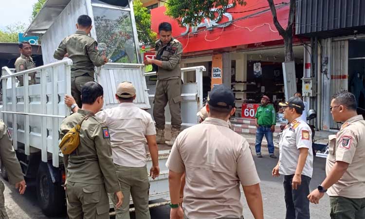 Petugas Satpol PP Kota Probolinggo saat membawa salah satu gerobak PKL yang tak dibawa pulang pemiliknya usai jualan.
