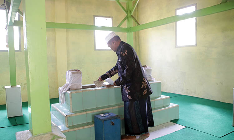 MAKAM: Petilasan Mbah Salam, di Dusun Wonosalam, Desa Kalisalam, Kecamatan Dringu. Tampak Sekretaris Desa Kalisalam, Kecamatan Dringu, Didik Saturin, 59, menata Surat Yasin di makam tersebut.