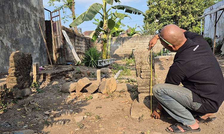UKUR: Budayawan Pasuruan, Tengku Mirza saat mengecek ukuran nisan yang terbuat dari batu andesit pada makam kuno itu.