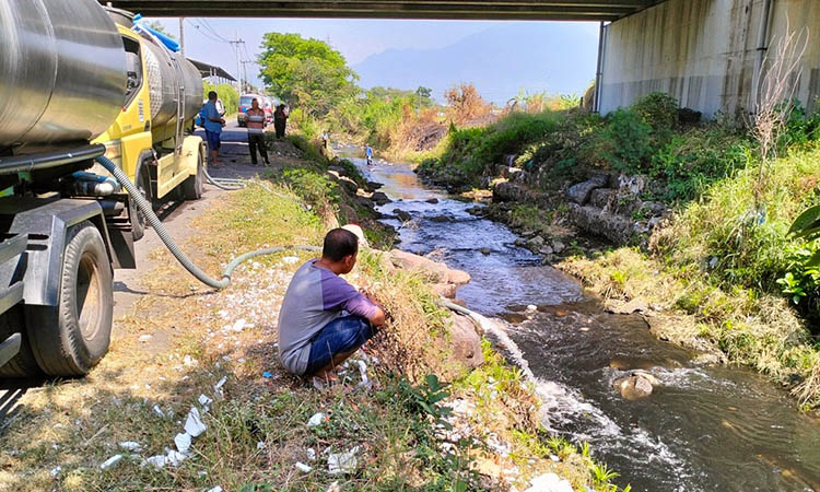 DIGELONTORI AIR: Selain pencemaran imbas limbah perusahaan, ternyata Kali Wangi juga dicemari oleh sampah rumah tangga. Tampak pekerja menggelontorkan air, untuk pembersihan Kali Wangi.