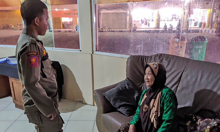 KETINGGALAN: Petugas saat meminta keterangan Senemi, lantaran ketinggalan rombongannya di Alun-alun Pasuruan.