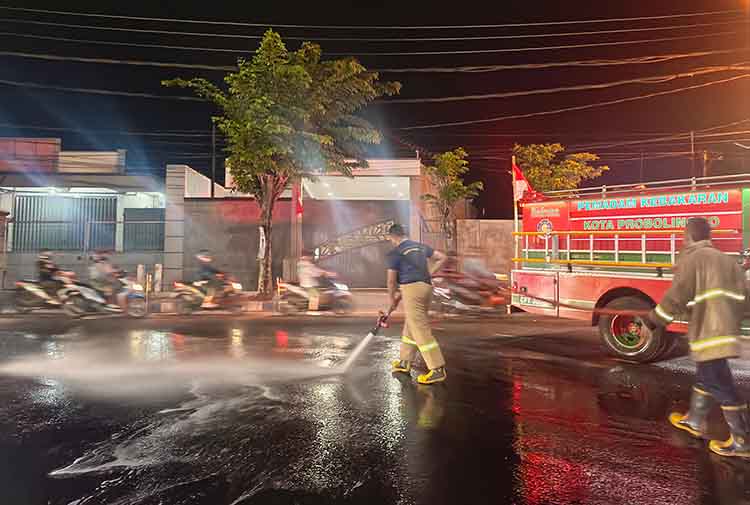 SIRAM: Tim Damkar Satpol PP Kota Probolinggo membersihkan tumpahan solar di tikugnan Jalan Pahlawan (Brak), Kota Probolinggo, Rabu (28/8) malam.
