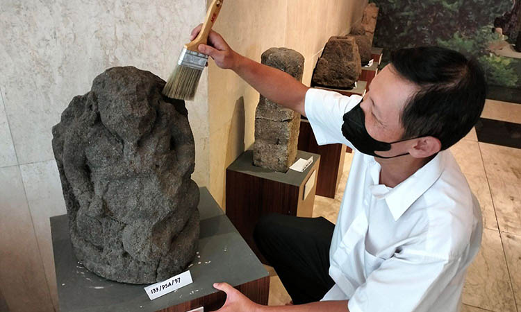 BERSIHKAN: Petugas Museum Cunggrang saat membersihkan salah satu peninggalan sejarah yang dipajang di museum setempat.