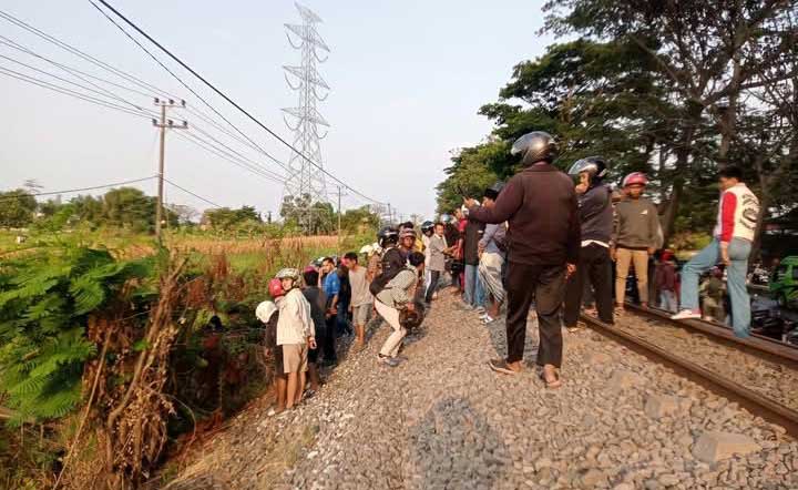 Petugas dibantu warga saat hendak mengevakuasi jenazah korban yang nekat menabrakkan diri ke KA Wijaya Kusuma.
