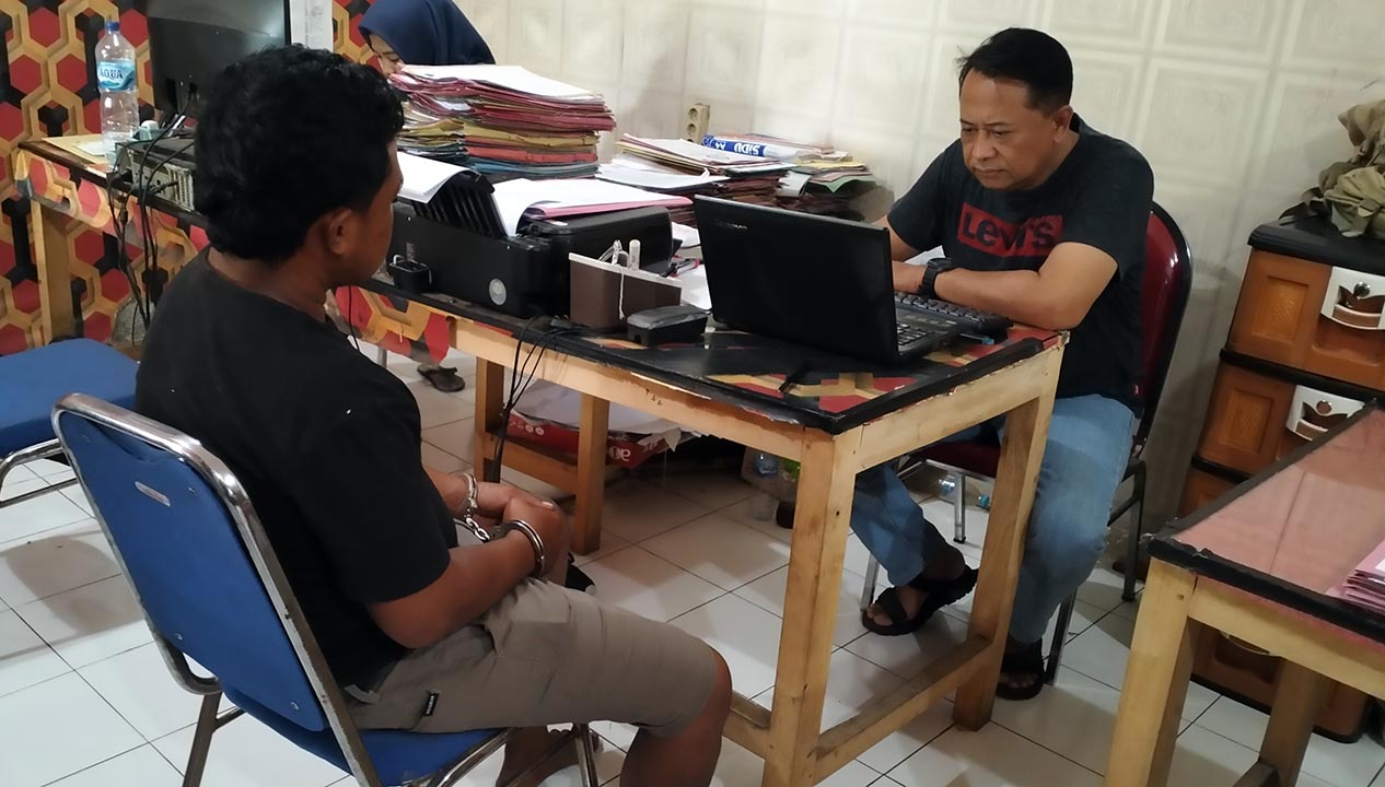 FZ, perangkat desa Rangkang, Kraksaan (kiri, tangan diborgol) saat diperiksa penyidik Satreskrim Polres Probolinggo.