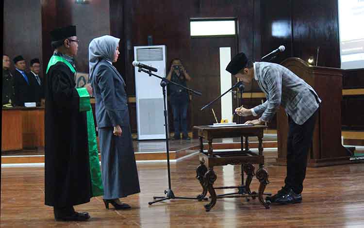 TANDA TANGAN: Ketua DPRD Kabupaten Probolinggo Oka Mahendra Jati Kusuma dan Alfiana Firda Afnaini menandatangani berita acara pelantikan yang diikuti rohaniawan.