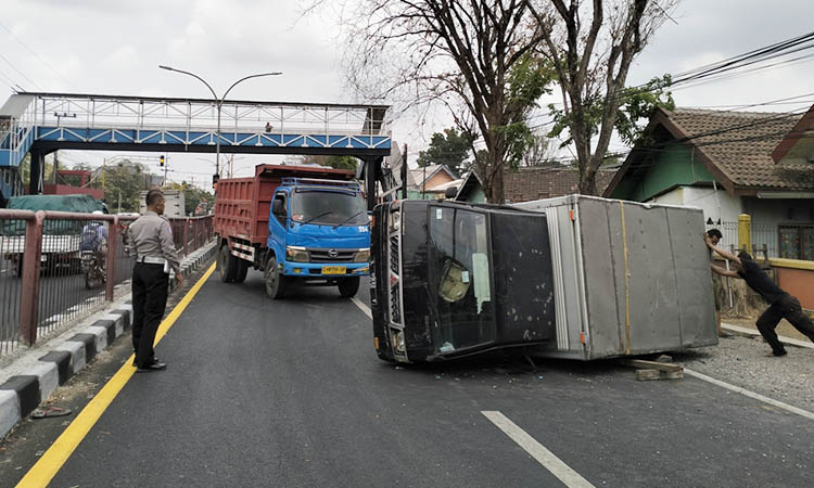 EVAKUASI: Pikap boks yang terguling di jalan. Petugas harus mengevakuasinya, untuk mengembalikan arus agar kembali normal.