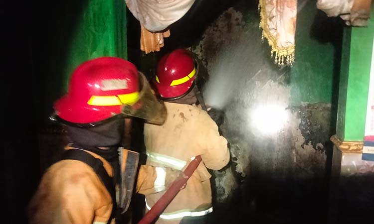 Petugas saat berupaya memadamkan api yang melalap ruang tamu rumah warga Kalirejo, Dringu usai motor listrik meledak.