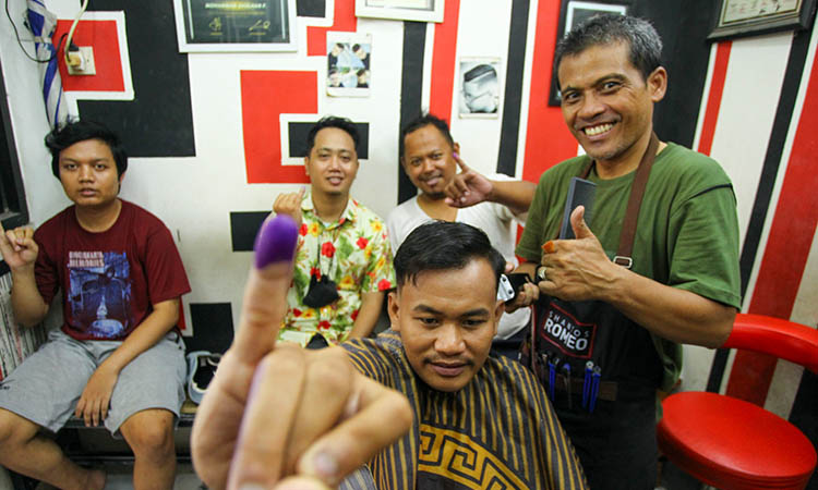 PANGKAS: Salah satu pemilih saat mendapatkan layanan pangkas rambut gratis di Hans Barber. Layanan gratis tersebut, untuk mendukung terselenggaranya pilkada 2024.