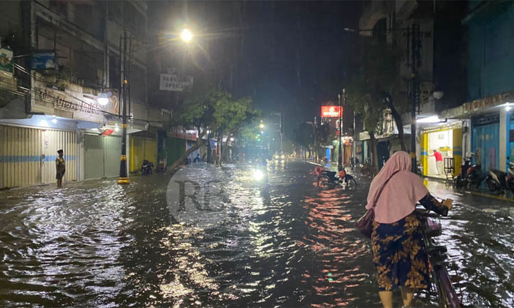 TERGENANG: Warga melintasi Jalan Wahid Hasyim Kota Pasuruan yang terendam air setelah hujan deras mengguyur sejak Kamis (5/12) sore.