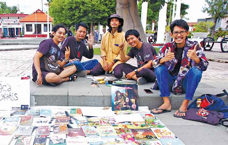 BERBAGI ILMU: Ilham Afrizal F (kanan), bersama sejumlah rekannya menyiapkan buku bacaan gratis di Taman Kota, Kota Pasuruan.