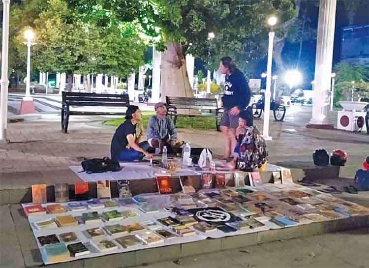 SAMPAI MALAM: Ilham Afrizal F bersama sejumlah rekannya menyiapkan buku bacaan gratis di Taman Kota, Kota Pasuruan, sampai malam.