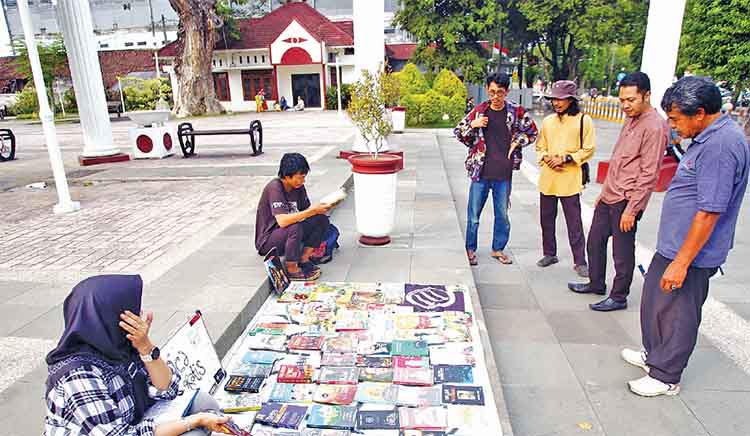 CARI DULU: Sejumlah pengujung mengamati sejumlah buku yang disiapkan Ilham Afrizal F, bersama sejumlah rekannya di Taman Kota, Kota Pasuruan.