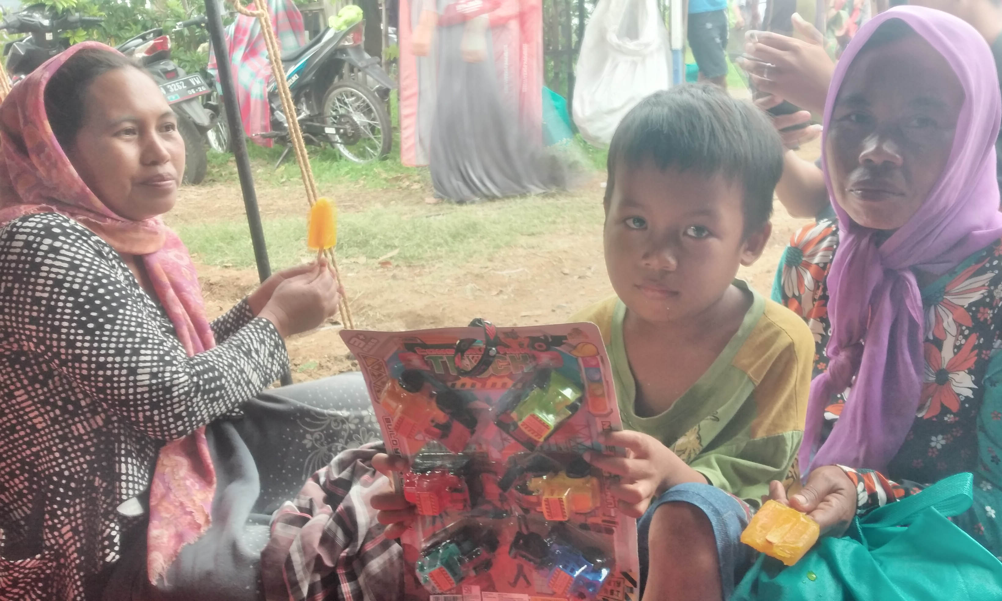 BUAT PENGHIBUR: Siti Fatimah dan anaknya yang membawa mainan pemberian dari Mensos, saat mengungsi di tenda milik BPBD saat banjir melanda di Desa Jarangan, Minggu (