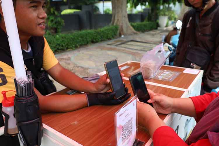 MODERN: Salah seorang warga penikmat kopi keliling melakukan pembacara secara elektornik.