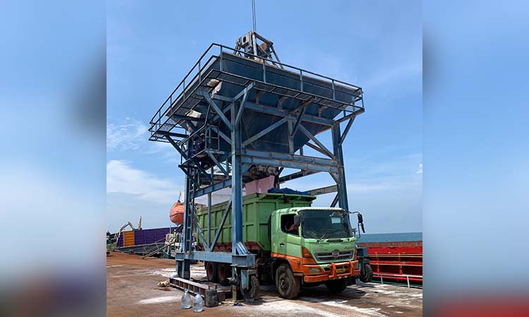 Proses pemindahan pupuk curah dari kapal ke truk yang memuat pupuk.